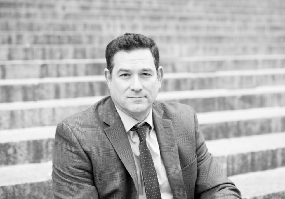 A man in suit and tie sitting on steps.